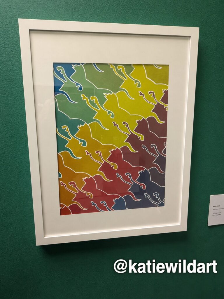 A framed print of interlocking animal shapes shading from green through yellow and red to purple