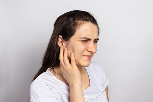 A woman winces and holds the side of her jaw