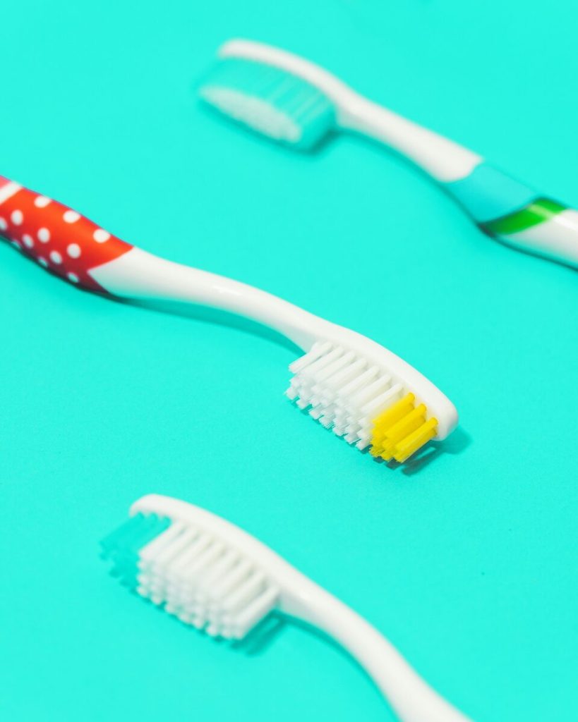 Three toothbrushes on a bright turquoise background